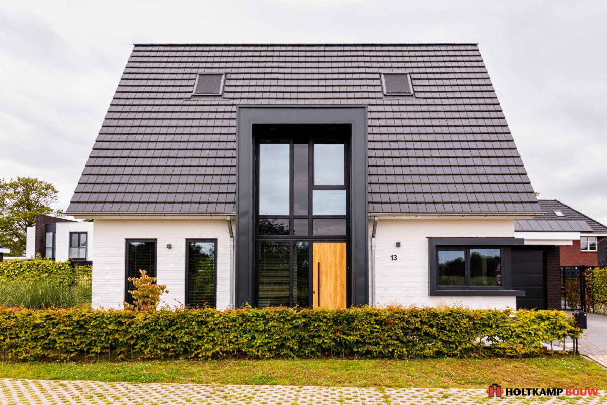 Voorgevel met risaliet en entreeportaal - Hagenborg 13, een eigentijds ontwerp van Holtkamp Bouw met een strak risaliet, wit gekeimde gevel en vlakke keramische dakpannen.