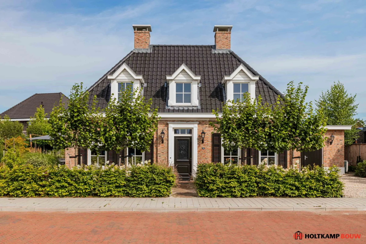 Voorzijde van een traditionele notariswoning met een eigentijds karakter, voorzien van een symmetrische gevel, twee schoorstenen en klassieke dakkapelle