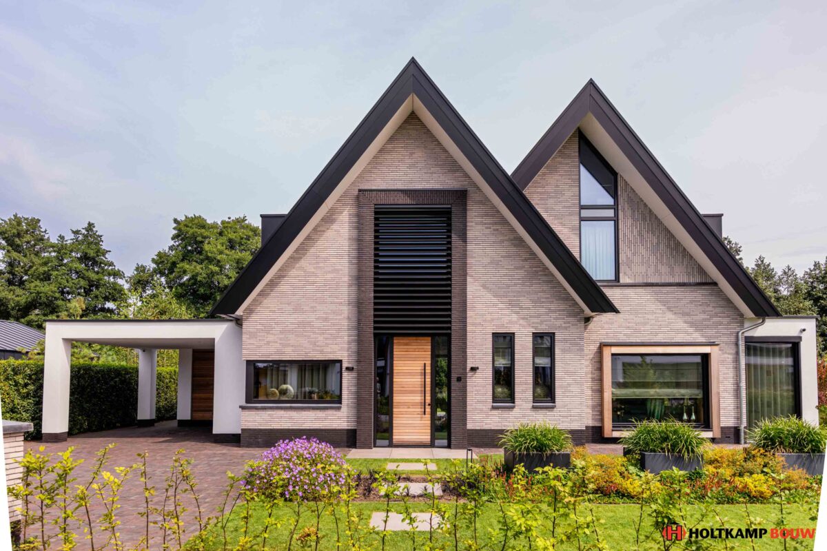 Moderne schuurwoning met antraciet zwarte kozijnen (RAL 9021) en natuurlijke houtkleur, breedte gesitueerd door Holtkamp Bouw