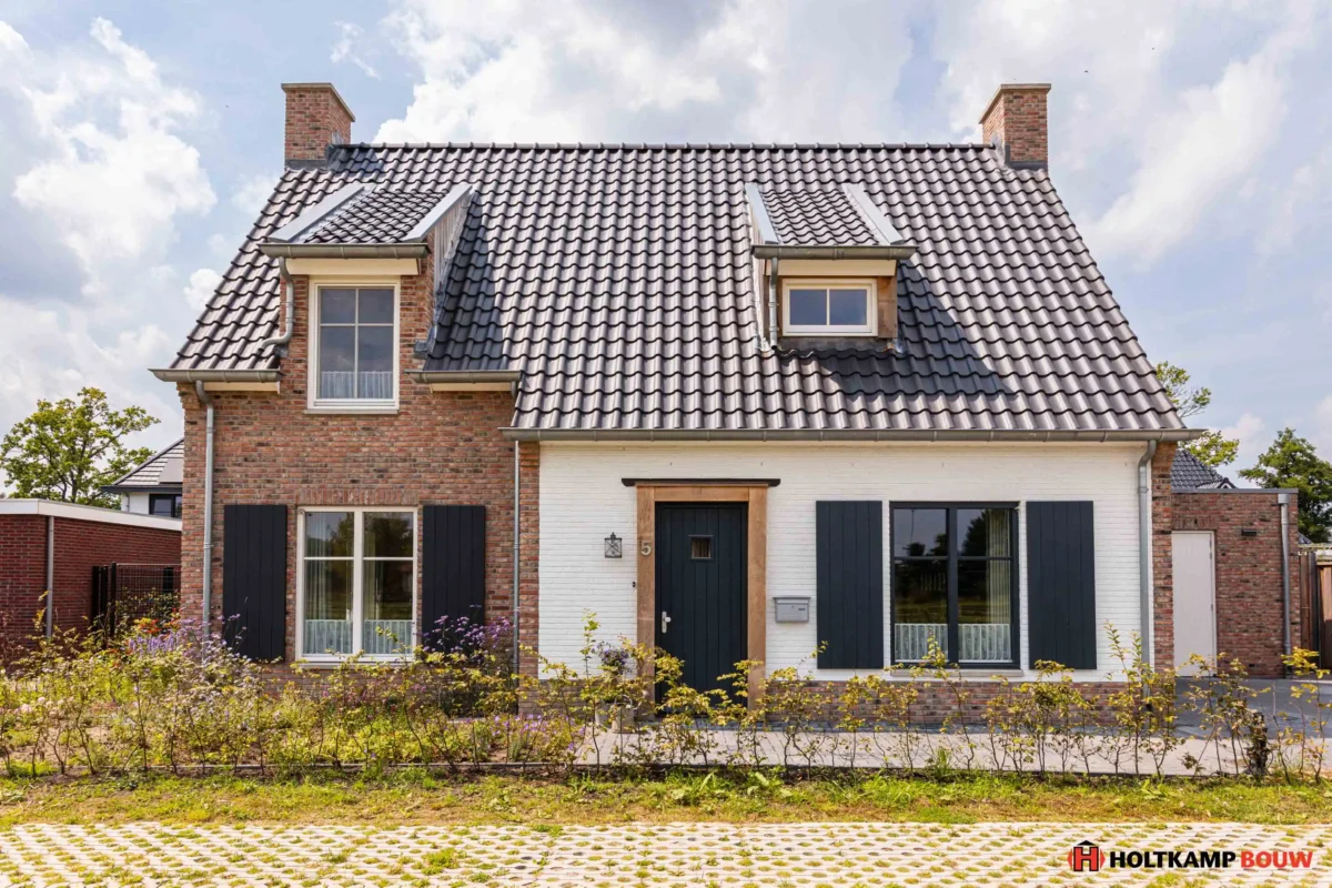 Voorgevel van een eigentijdse vrijstaande woning met natuurlijke houtkleurige accenten, ontworpen door Holtkamp Bouw in Hengelo