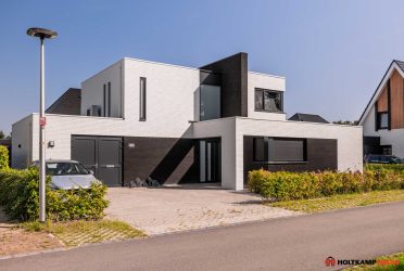 Breedte gesitueerde villa met wit gesausde gevel in wildverband