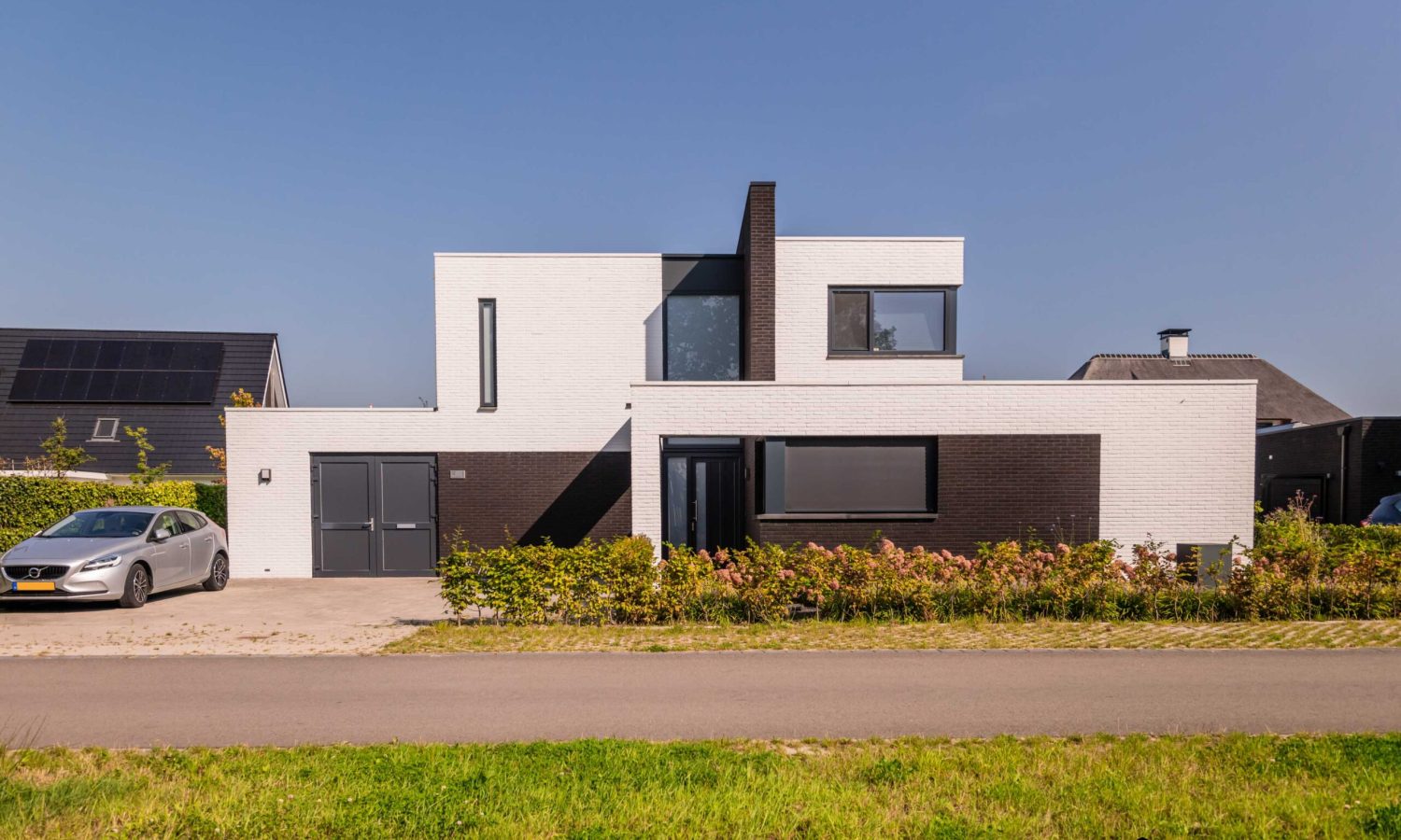 igentijdse vrijstaande villa met wit gesausde gevel, breedte gesitueerd, gebouwd door Holtkamp Bouw in Hengelo