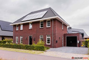 Eigentijdse vrijstaande woning met een moderne uitstraling, wit gekeimd en wit gesausd met donkere plintsteen.
