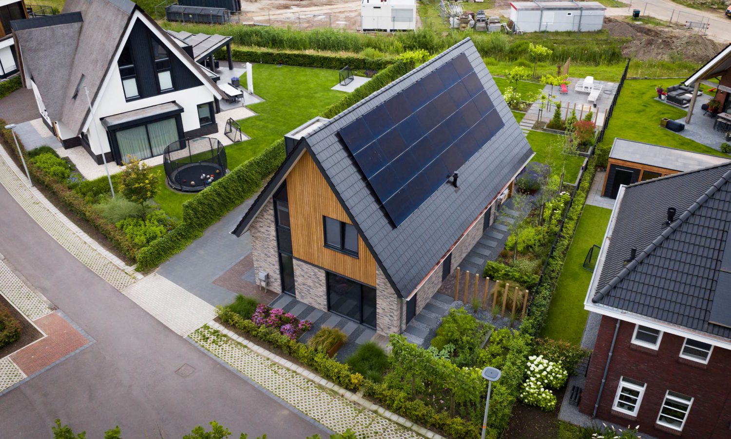 Luchtfoto van de woning en omgeving, waarop de moderne schuurwoning, zonnepanelen en het groene landschap te zien zijn