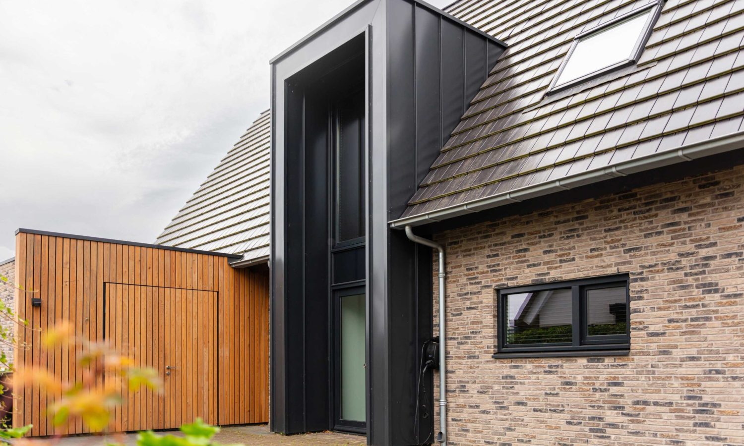 etail van het risaliet bekleed met zwarte staalplaat in een RAL 9021 klik fels-systeem, wat zorgt voor een modern accent bij de entree.