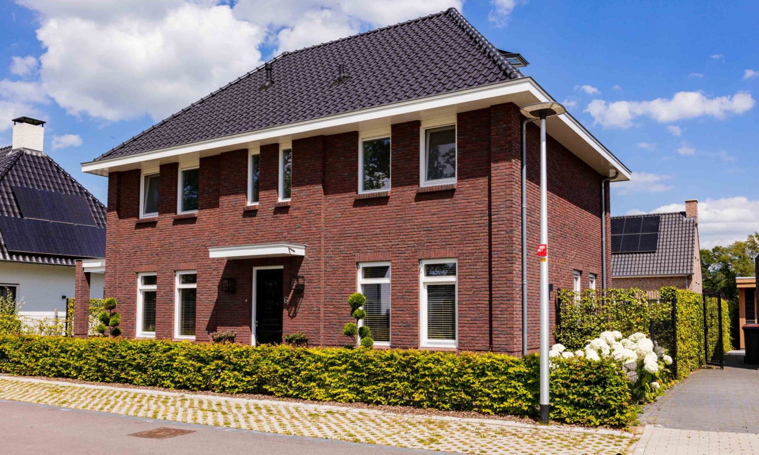 Vooraanzicht van een eigentijdse notariswoning in Hengelo, ontworpen door Holtkamp Bouw. De woning is breed gesitueerd en heeft een getimmerde bakgoot.