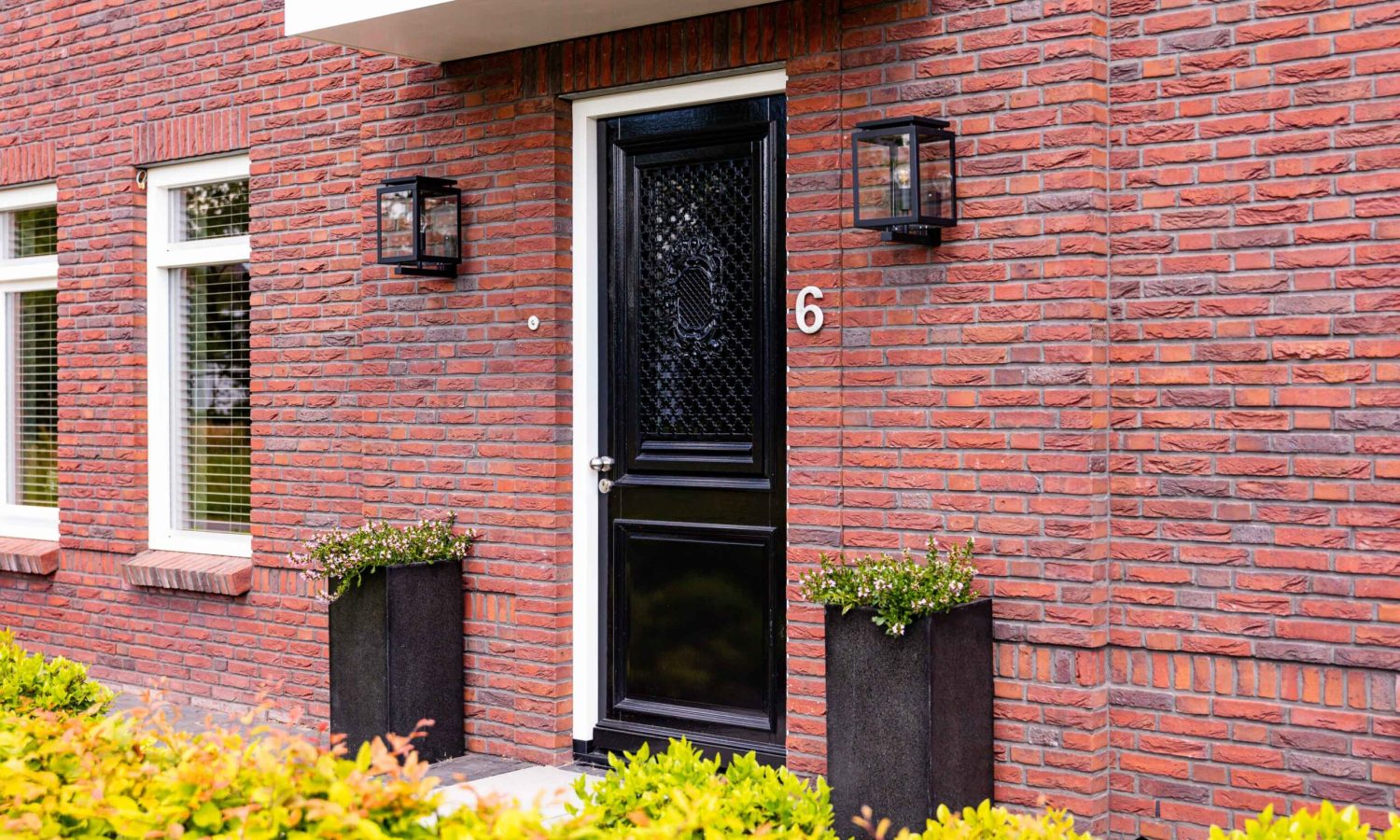 Detailopname van de voordeur van de notariswoning, met een karakteristiek zwart deurontwerp en stijlvolle buitenlampen.