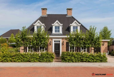 Voorzijde van een traditionele notariswoning met een eigentijds karakter, voorzien van een symmetrische gevel, twee schoorstenen en klassieke dakkapelle