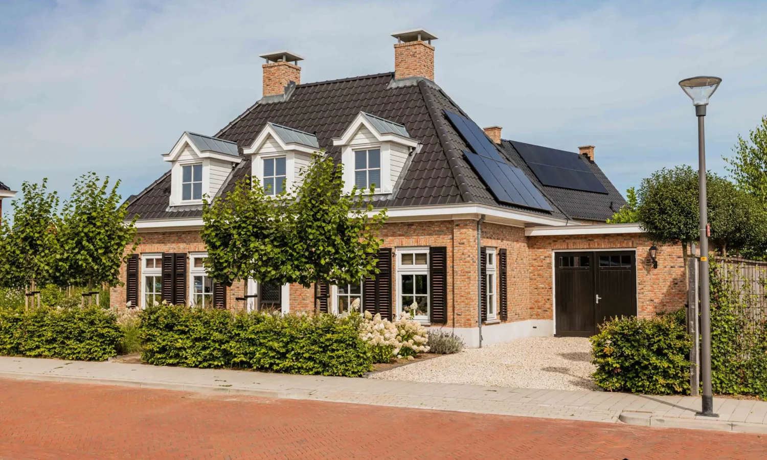 Zijaanzicht van een eigentijdse notariswoning met brede situering, een getimmerde bakgoot en zinken regenpijp met bladvanger.