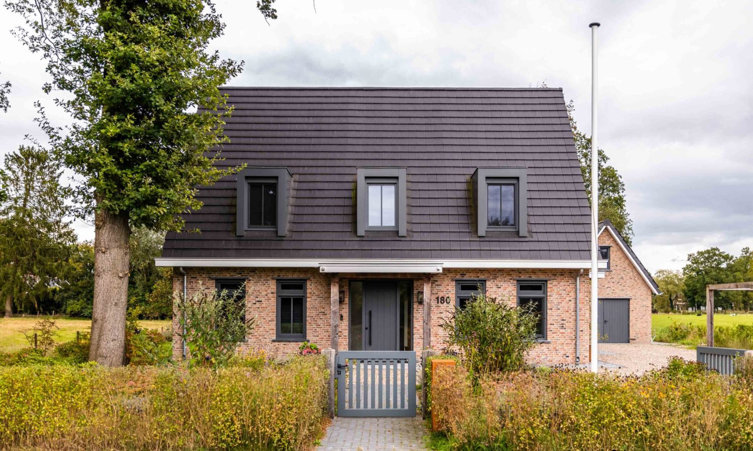 Detail van luifel boven voordeur en zinken regenpijp met bladvanger bij villa in Lonneker, Holtkamp Bouw
