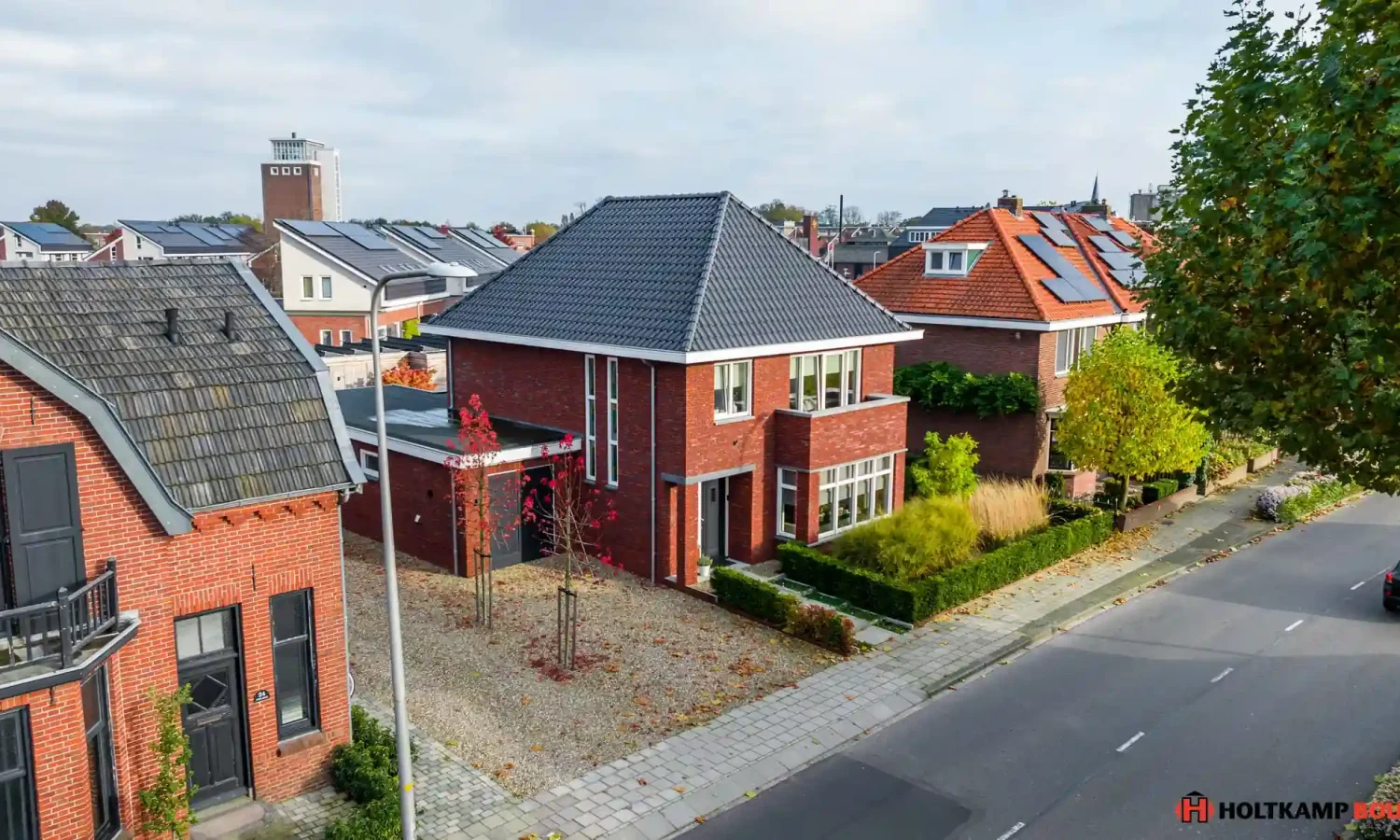 Luchtfoto van een breedte gesitueerde moderne woning in Haaksbergen met getimmerde bakgoot en strak aangelegde voortuin, gerealiseerd door Holtkamp Bouw