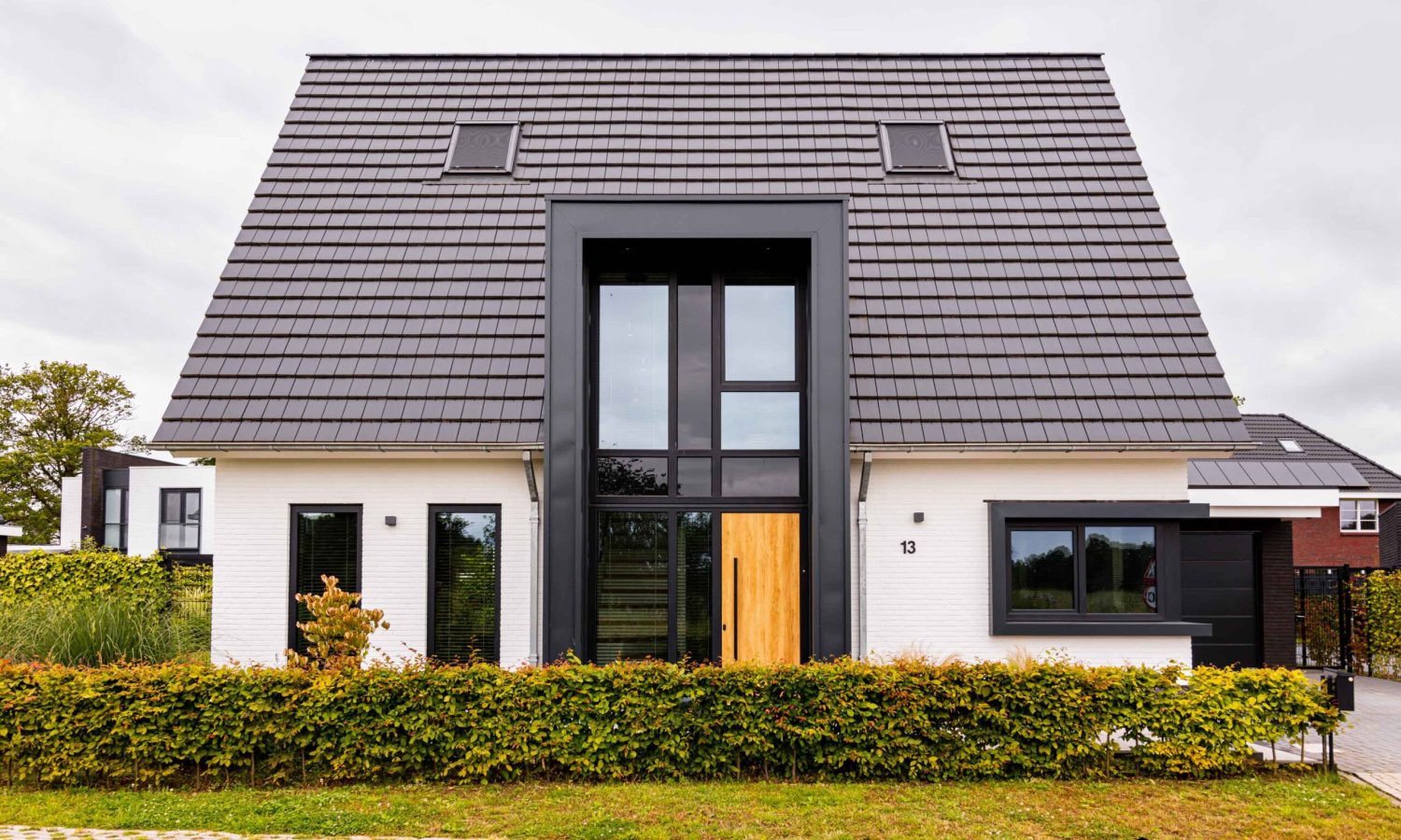 Voorgevel met risaliet en entreeportaal - Hagenborg 13, een eigentijds ontwerp van Holtkamp Bouw met een strak risaliet, wit gekeimde gevel en vlakke keramische dakpannen.