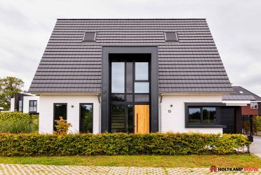 Voorgevel met risaliet en entreeportaal - Hagenborg 13, een eigentijds ontwerp van Holtkamp Bouw met een strak risaliet, wit gekeimde gevel en vlakke keramische dakpannen.