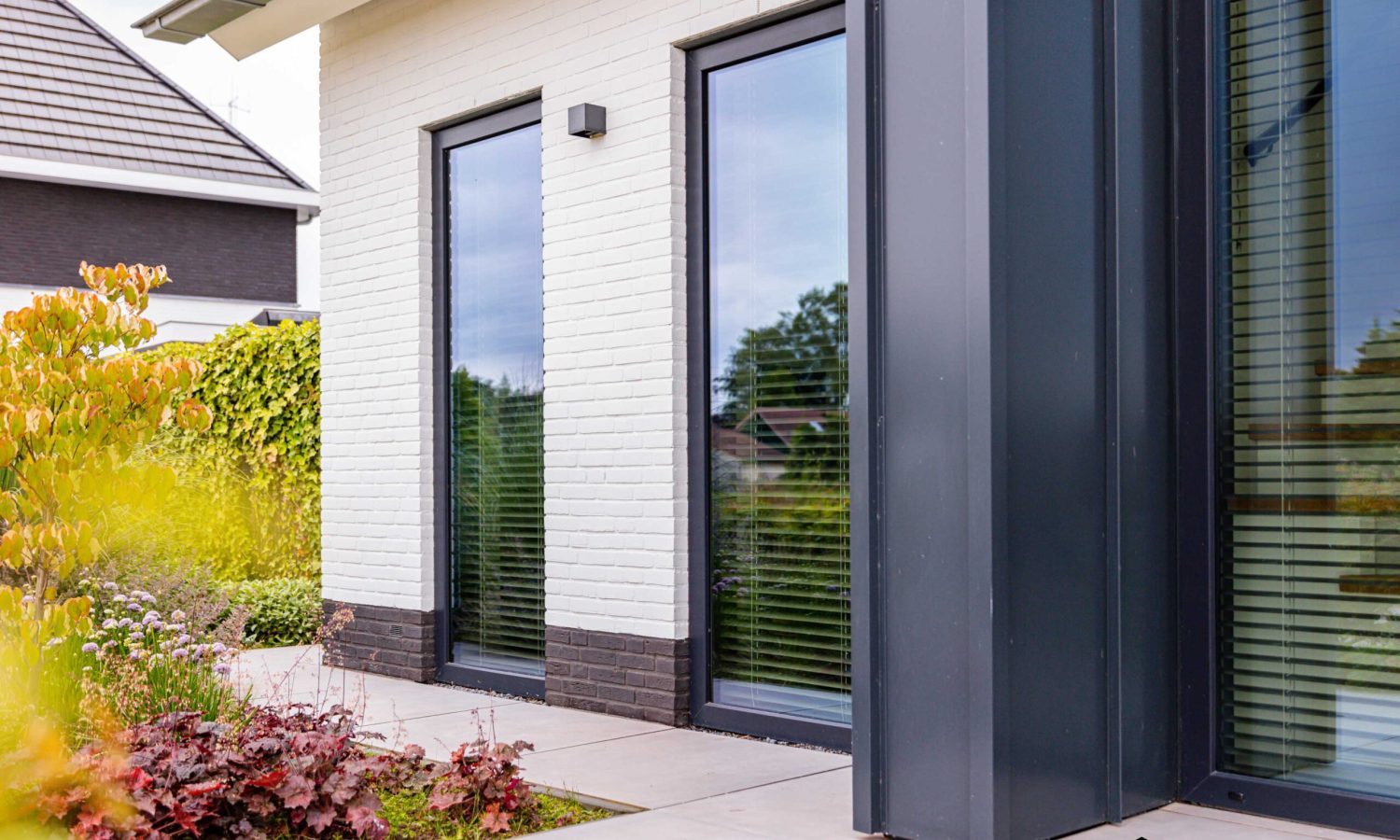 Zijaanzicht met hoekkozijn en spekband - De woning heeft een breed gesitueerde opzet, met spekbanddetails en hoekkozijnen voor extra lichtinval.