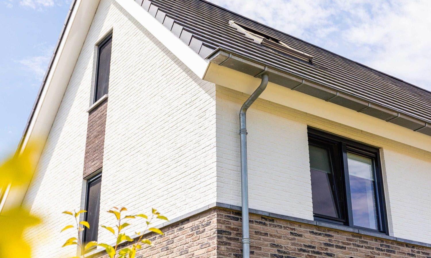 Detailfoto van het trasraam en de antraciete raamdorpels. Hoogwaardige zinken afwerking, inclusief bakgoten en bladvanger.