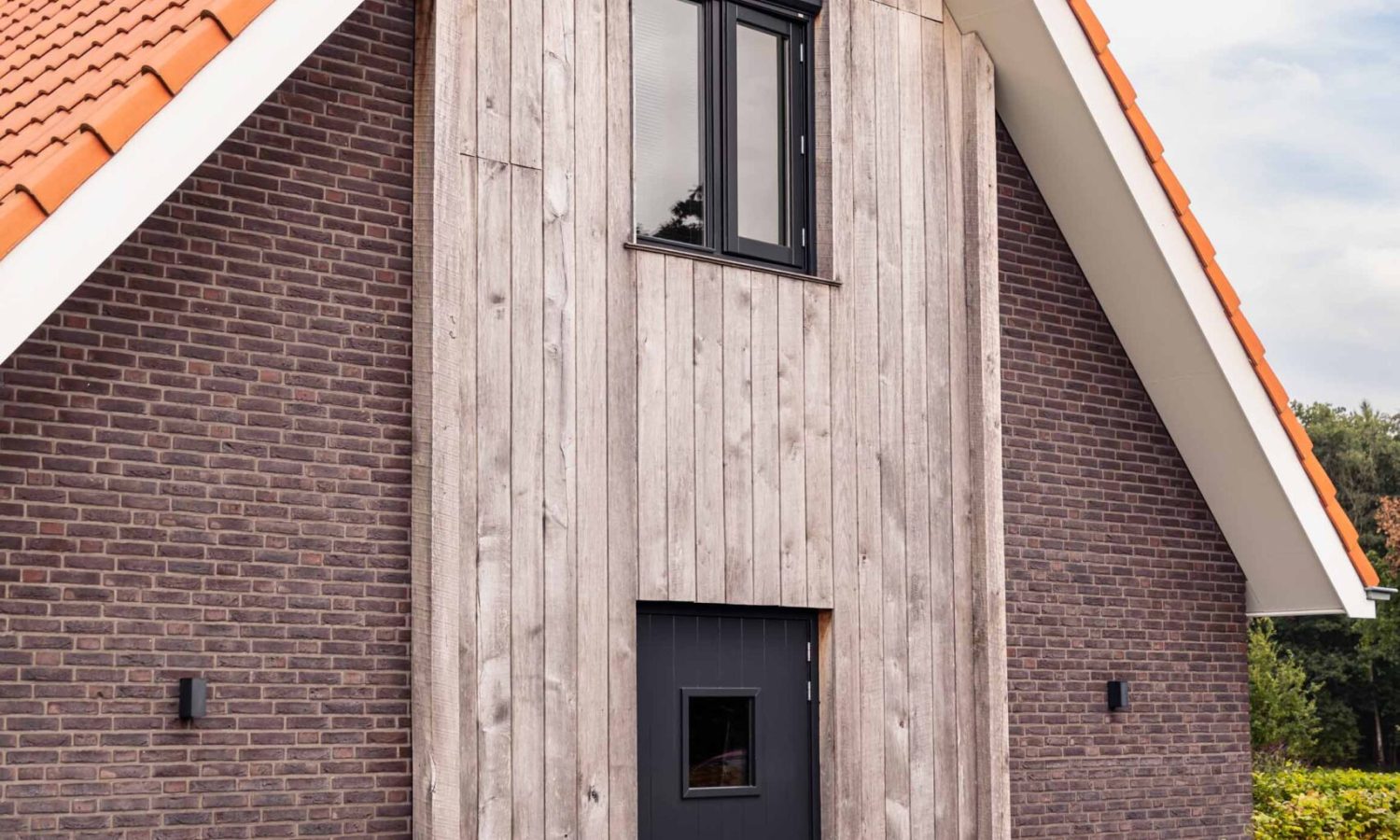 Eigentijdse schuurwoning in Enschede, voorzien van natuurlijke houtkleur en zinken bakgoten, ontworpen door Holtkamp Bouw