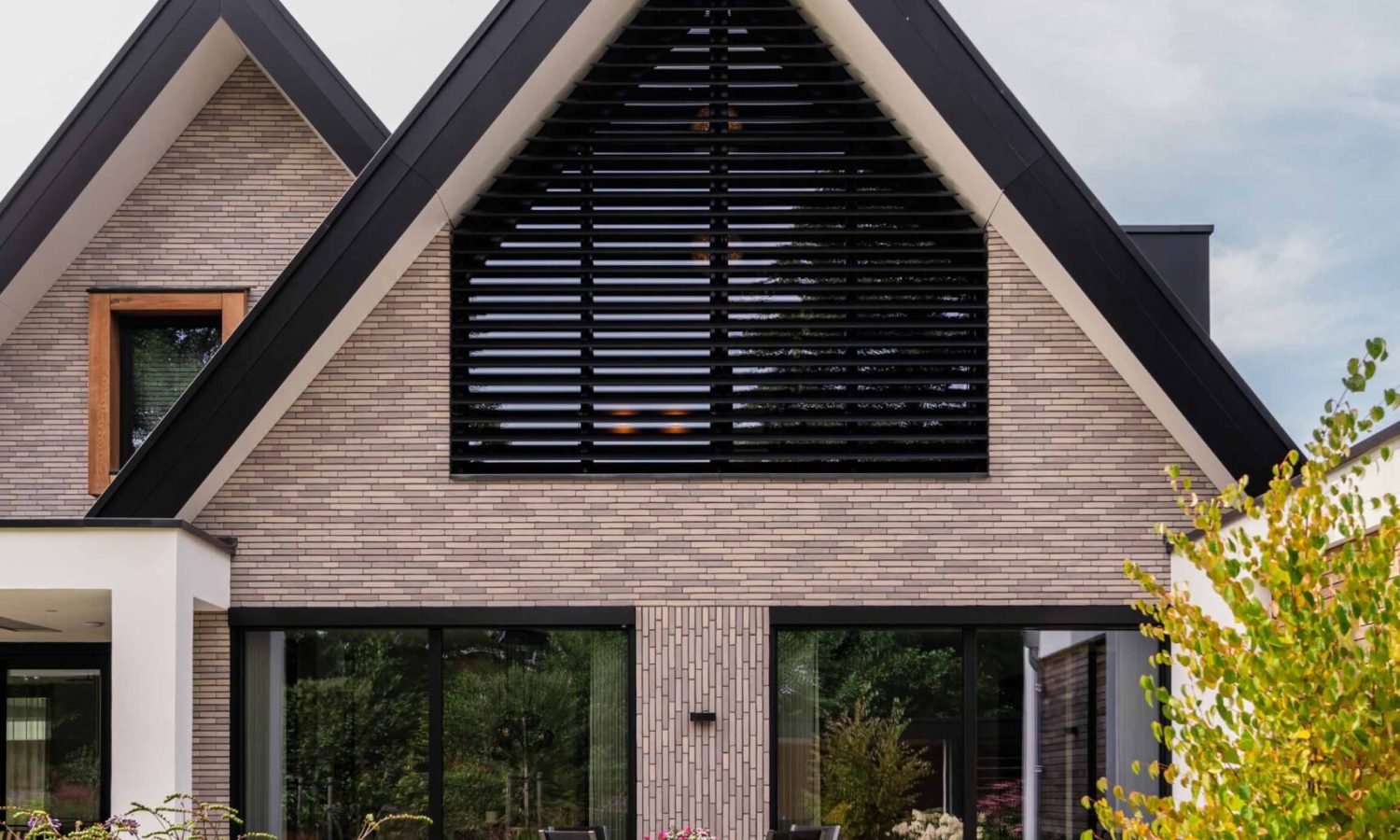 Voorzijde eigentijdse schuurwoning in Enschede, breedte gesitueerd met natuurlijke houtkleur en moderne kozijnen