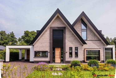 Moderne schuurwoning met antraciet zwarte kozijnen (RAL 9021) en natuurlijke houtkleur, breedte gesitueerd door Holtkamp Bouw