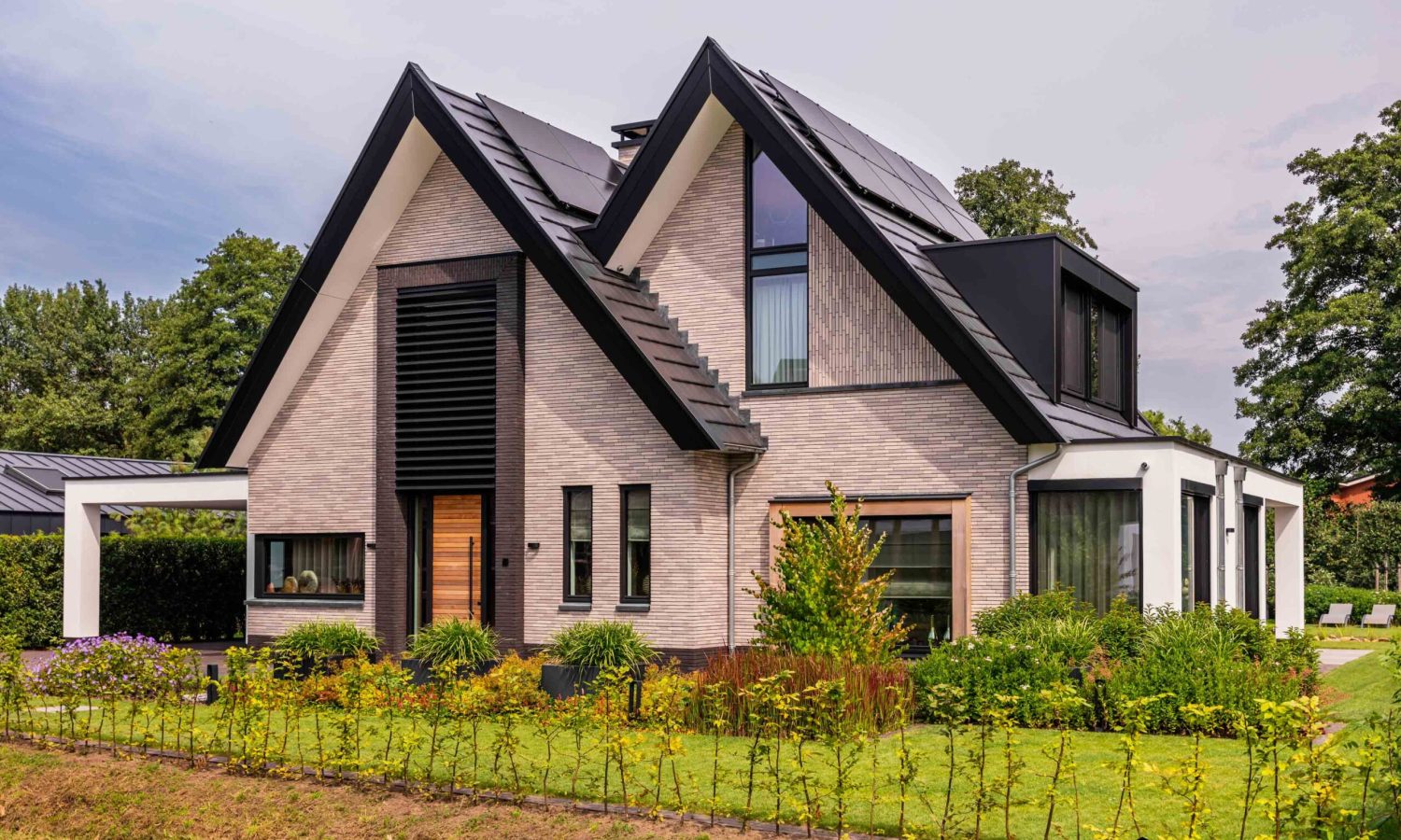 Voorzijde eigentijdse schuurwoning in Enschede, breedte gesitueerd met natuurlijke houtkleur en moderne kozijnen
