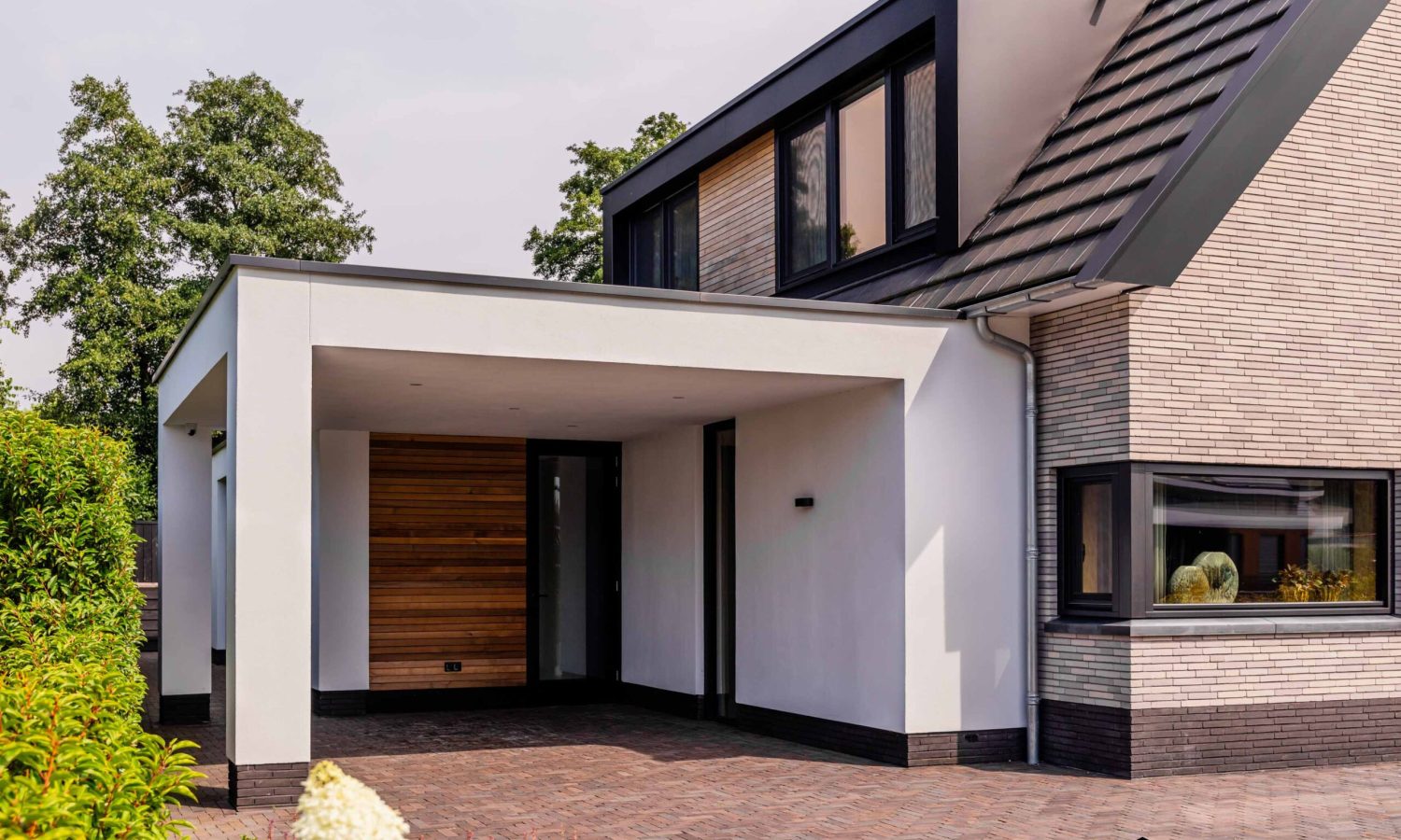 Detail van zinken regenpijp met bladvanger bij schuurwoning met antraciet zwarte kozijnen, Holtkamp Bouw