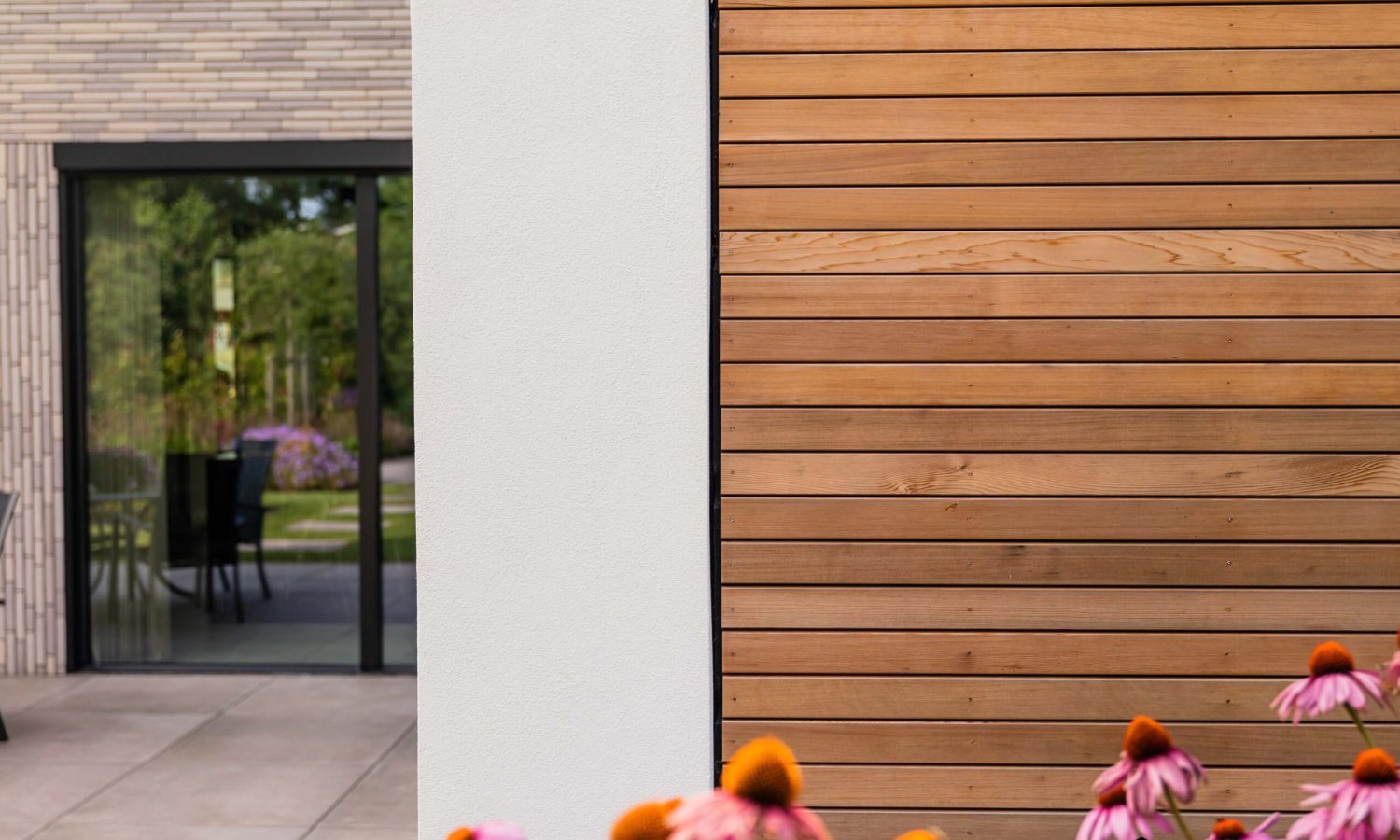 Zijaanzicht van breedte gesitueerde schuurwoning met antraciet zwarte kozijnen en natuurlijke houtkleur gevel