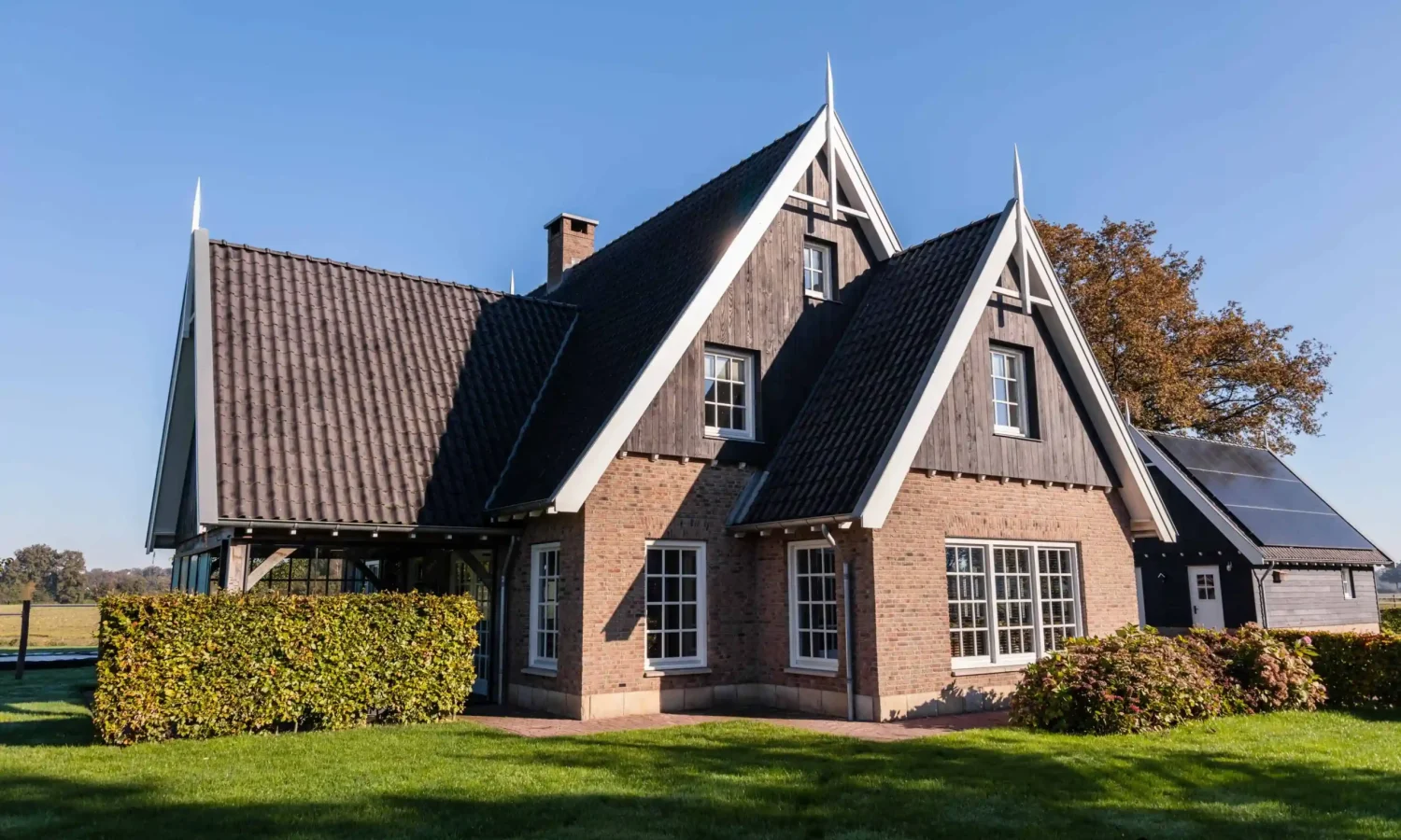 Schuurwoning in landelijke stijl met natuurlijke houtkleur en zinken regenpijp met bladvanger, ontworpen door Holtkamp Bouw