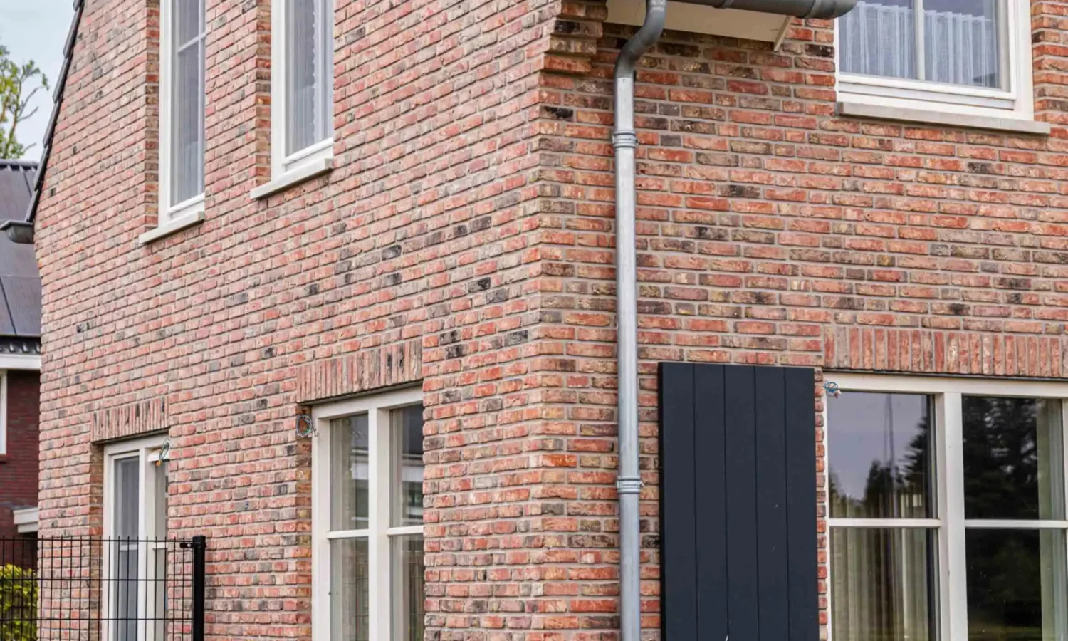 ijaanzicht van de woning met zicht op de natuurlijke bakstenen en houten gevelafwerking