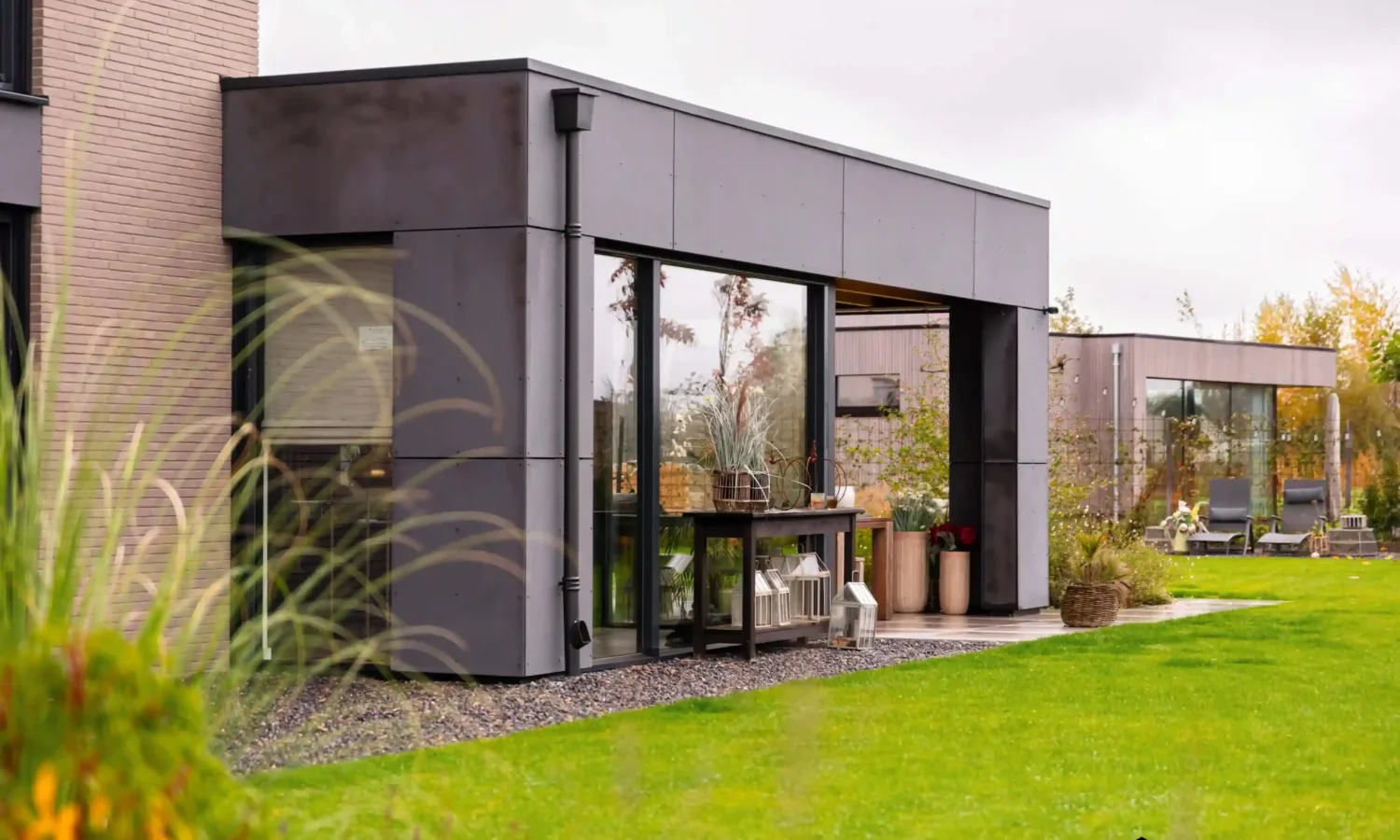 Achterzijde van een moderne villa met grote glazen schuifpuien en een overdekte buitenruimte