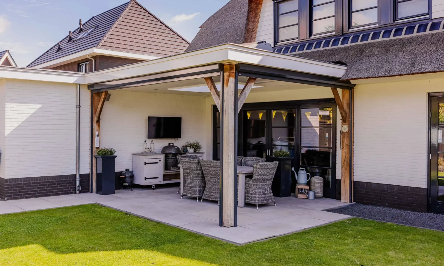 Moderne uitbouw met overdekt terras en open woonruimte, voorzien van luxe buitenkeuken.