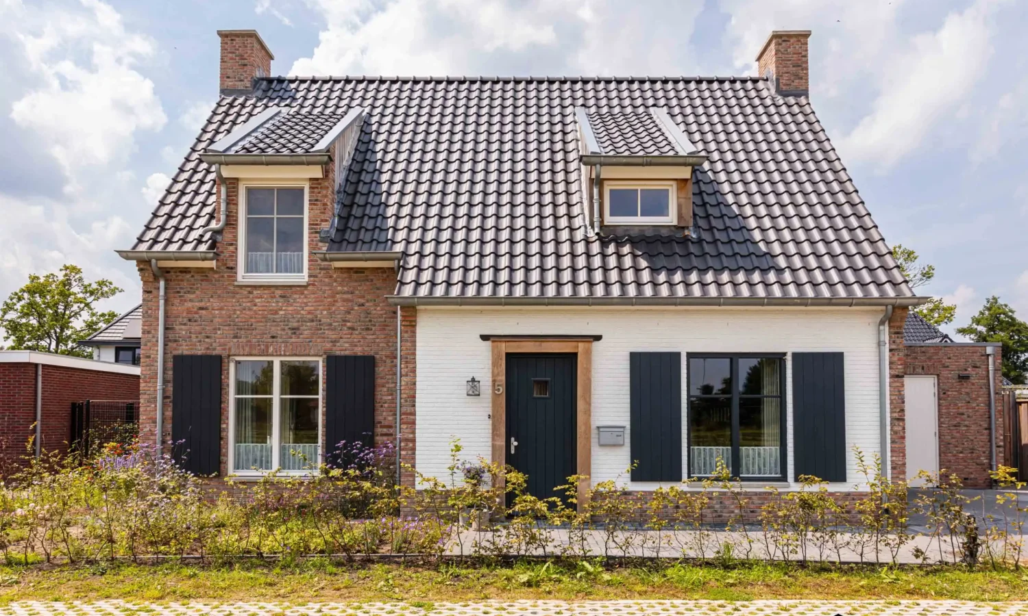 Voorgevel van een eigentijdse vrijstaande woning met natuurlijke houtkleurige accenten, ontworpen door Holtkamp Bouw in Hengelo