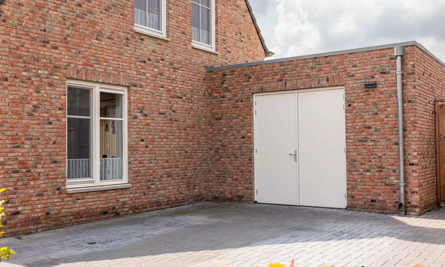 Zijaanzicht van de woning met zicht op de natuurlijke bakstenen en houten gevelafwerking